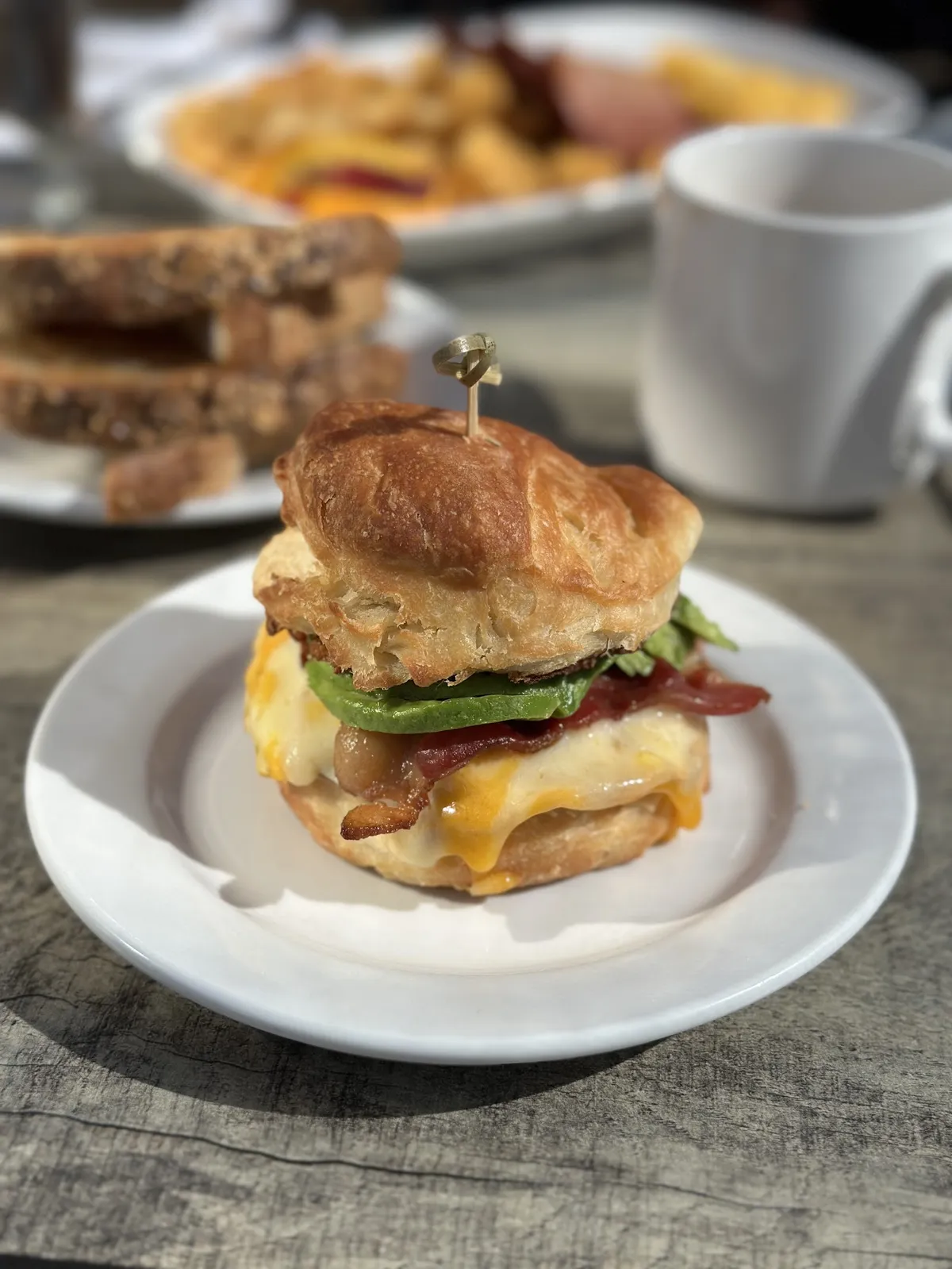Croissant breakfast sandwich with bacon, egg, cheese, and avocado