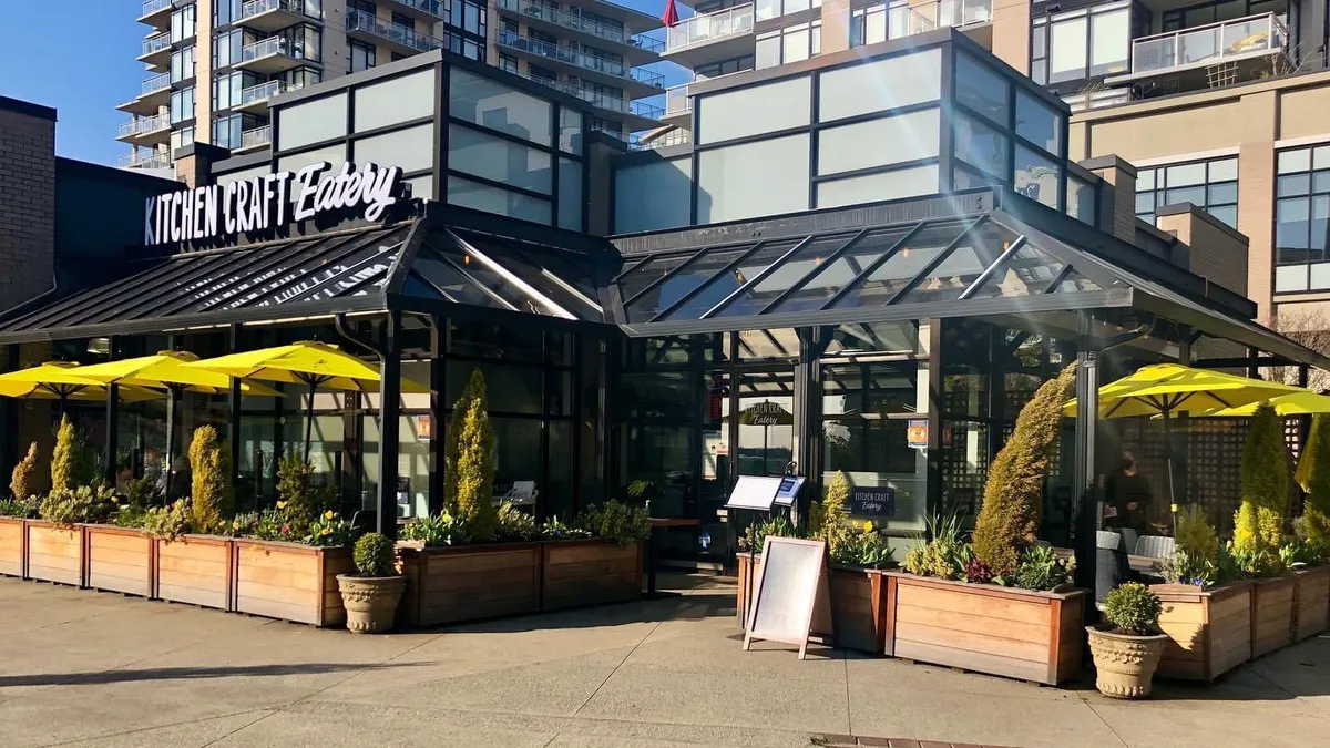 Restaurant storefront with patio, yellow umbrellas, and planters